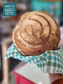 Pain de campagne sur une planche en bois avec croûte dorée et mie alvéolée.